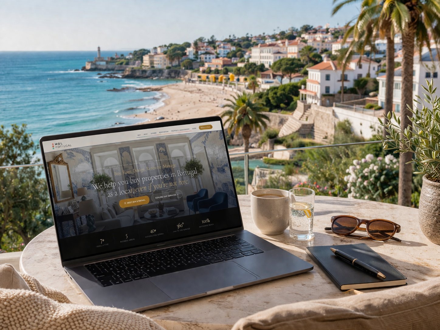 Laptop showing property listings on a Portuguese terrace, overlooking Cascais coastline