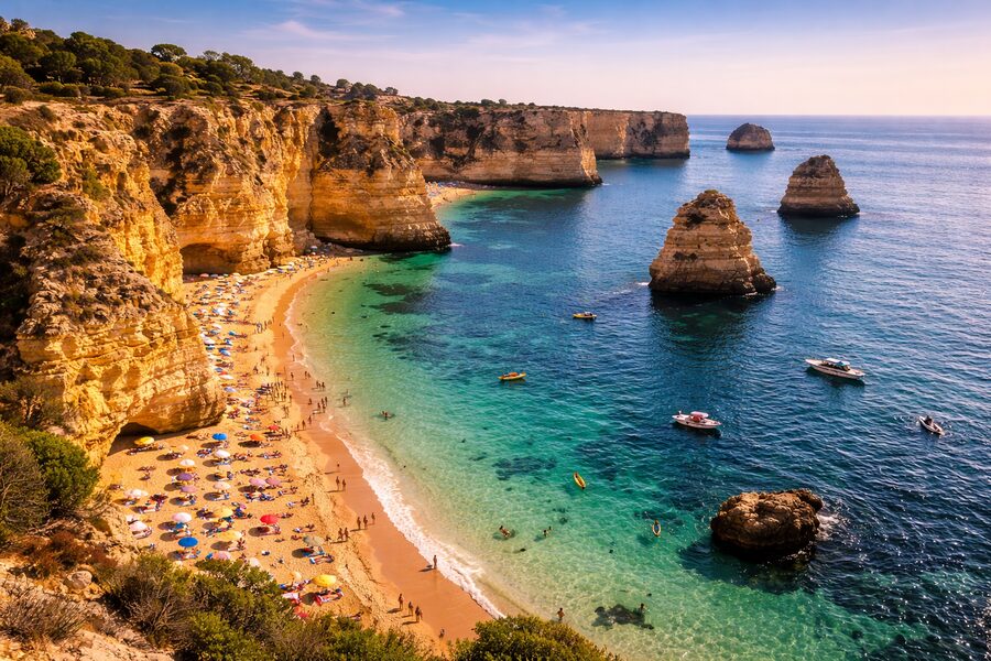 Dramatic Algarve coastline with cliffs, turquoise water, and a sandy beach