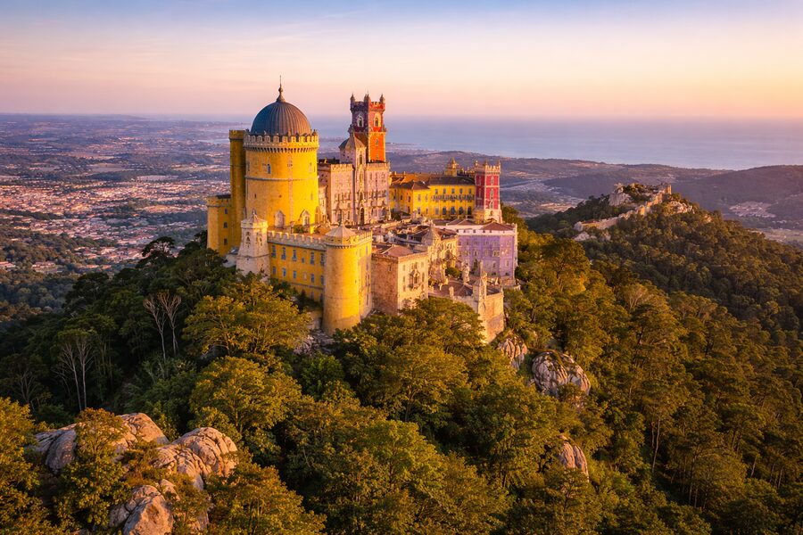 Pena Palace on a forested hilltop in Sintra at sunset